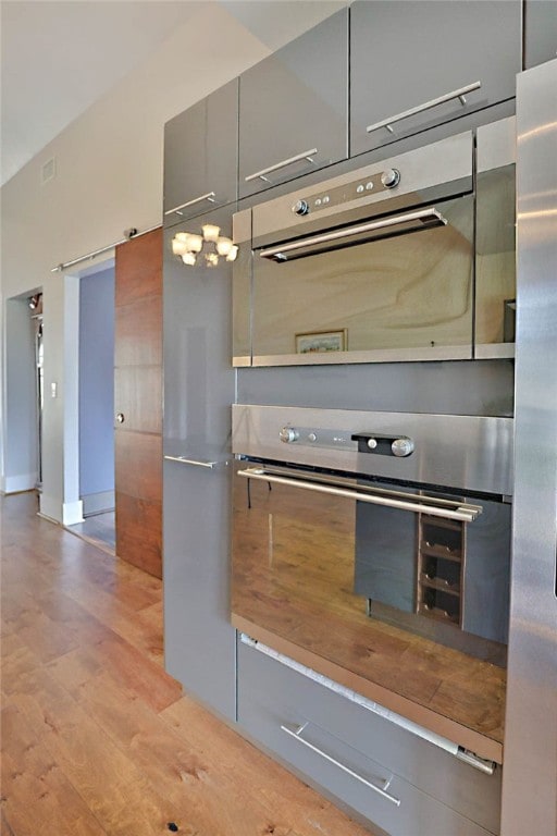 kitchen featuring double oven, gray cabinets, baseboards, modern cabinets, and light wood-style floors