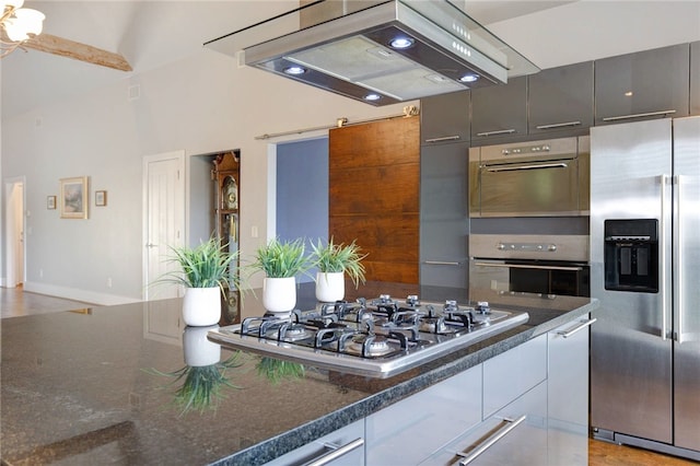 kitchen featuring modern cabinets, stainless steel appliances, dark stone counters, and under cabinet range hood