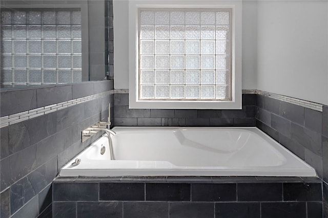 bathroom featuring a garden tub and a healthy amount of sunlight