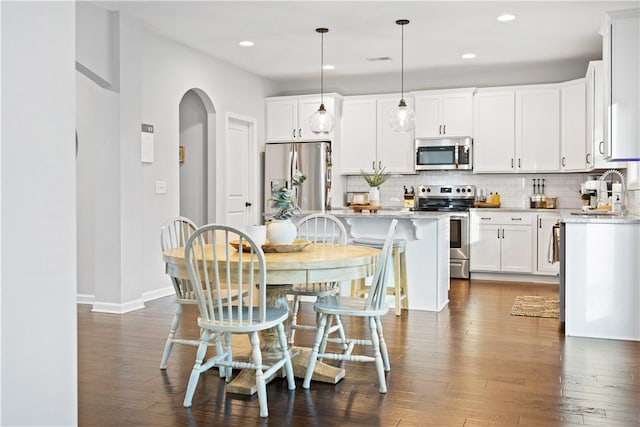 kitchen with decorative light fixtures, a center island, white cabinets, and appliances with stainless steel finishes