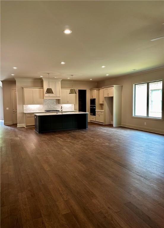 465 Windsor Dr, Opelika, AL 36801 - kitchen featuring an island with sink, ornamental molding, white cabinets, dark wood-style floors, and baseboards