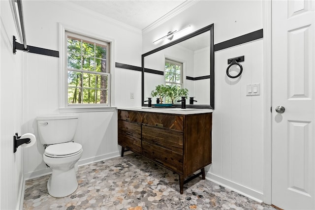 bathroom featuring toilet, vanity, a healthy amount of sunlight, and ornamental molding