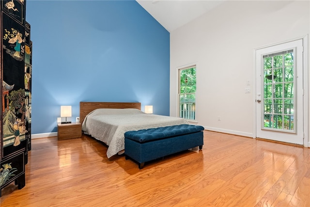 bedroom featuring access to outside, high vaulted ceiling, and light hardwood / wood-style floors