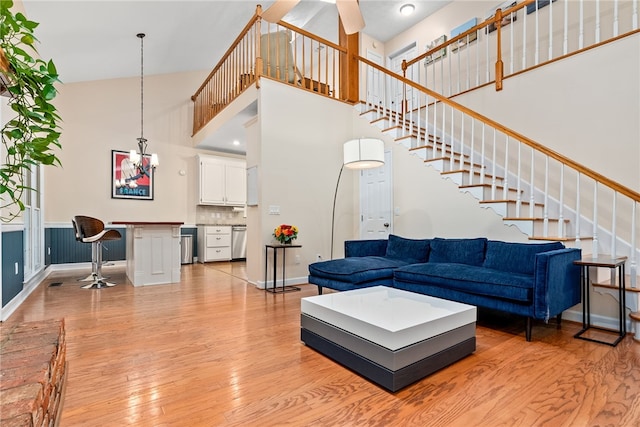 living room with ceiling fan, a towering ceiling, and light hardwood / wood-style floors