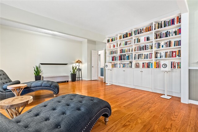 living area with light wood-type flooring and built in features