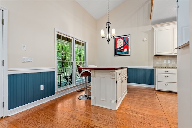 kitchen featuring a breakfast bar, hanging light fixtures, tasteful backsplash, a kitchen island, and white cabinetry