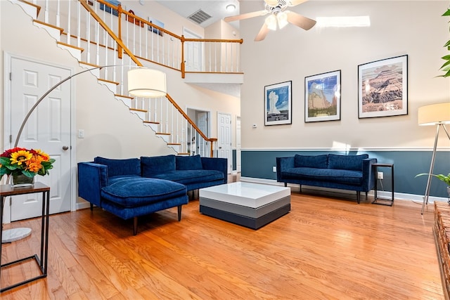 living room with ceiling fan, hardwood / wood-style floors, and a high ceiling