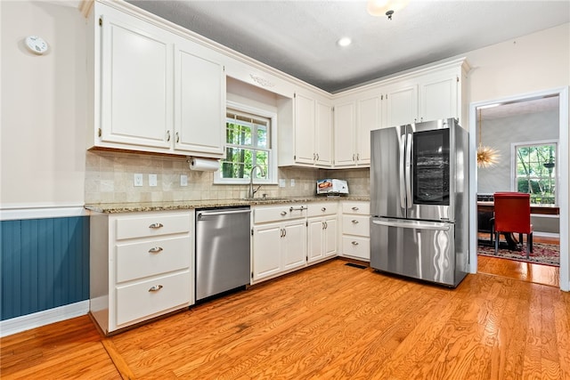 kitchen with white cabinetry, sink, appliances with stainless steel finishes, and light hardwood / wood-style flooring