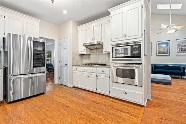 kitchen featuring decorative backsplash, appliances with stainless steel finishes, a skylight, ceiling fan, and white cabinetry