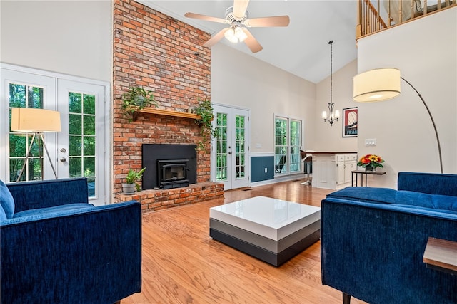 living room with a wood stove, french doors, ceiling fan with notable chandelier, a wealth of natural light, and wood-type flooring