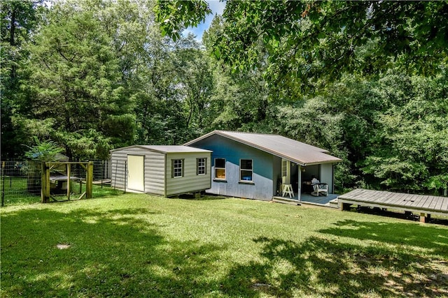 rear view of property with a lawn, a shed, and a wooden deck