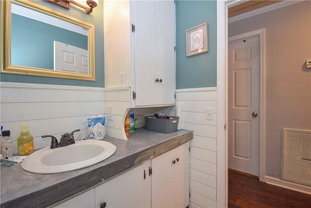 bathroom featuring hardwood / wood-style flooring, vanity, decorative backsplash, and ornamental molding