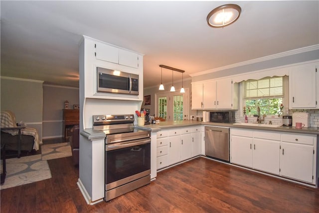 kitchen with decorative light fixtures, stainless steel appliances, white cabinetry, and sink