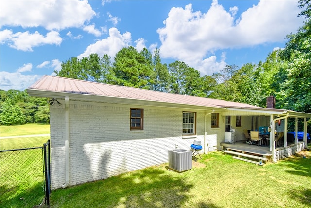 back of house featuring central AC unit and a lawn