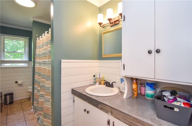 bathroom with ornamental molding, vanity, wooden walls, tile patterned flooring, and toilet