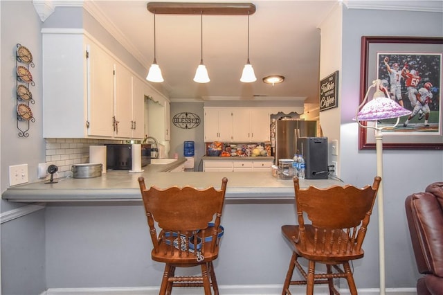 kitchen with white cabinets, tasteful backsplash, decorative light fixtures, kitchen peninsula, and a breakfast bar area