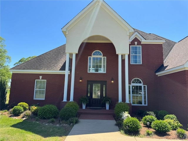view of front of house with brick siding and roof with shingles