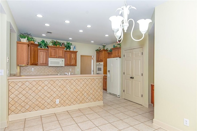 kitchen featuring decorative light fixtures, an inviting chandelier, white appliances, tasteful backsplash, and kitchen peninsula