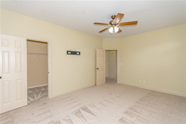 unfurnished bedroom with a walk in closet, a closet, ceiling fan, and light colored carpet