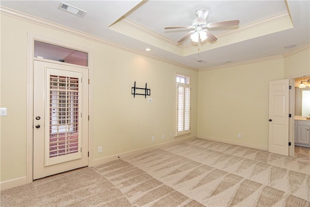 carpeted empty room featuring a raised ceiling, ceiling fan, and crown molding