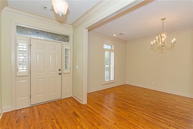 foyer with wood-type flooring, ornamental molding, a healthy amount of sunlight, and a notable chandelier