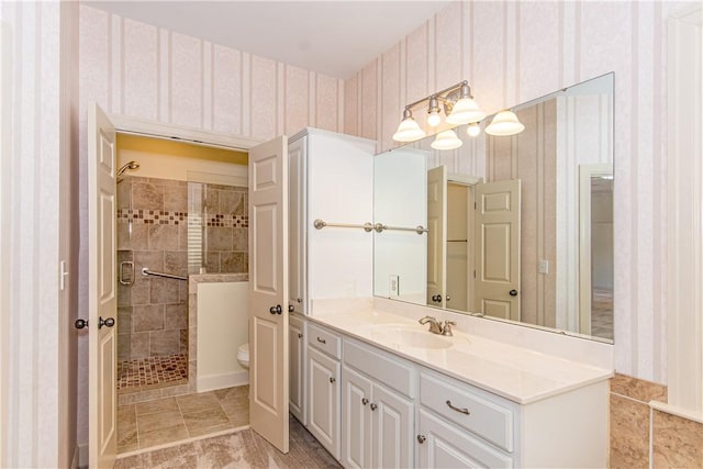 bathroom featuring a tile shower, vanity, and toilet