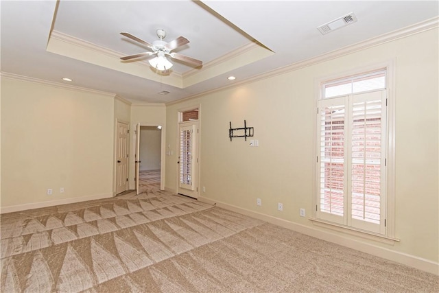 empty room featuring ornamental molding, ceiling fan, carpet floors, and a tray ceiling