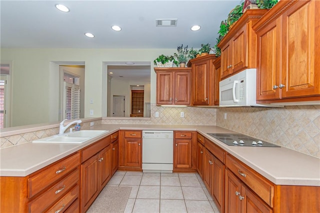 kitchen with white appliances, kitchen peninsula, light tile patterned floors, tasteful backsplash, and sink