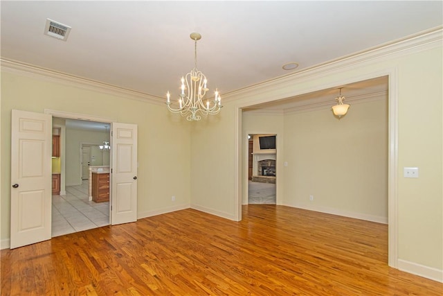 empty room with light hardwood / wood-style flooring, crown molding, and a chandelier