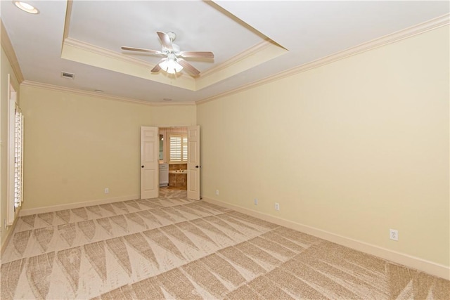 carpeted empty room with ceiling fan, crown molding, and a raised ceiling