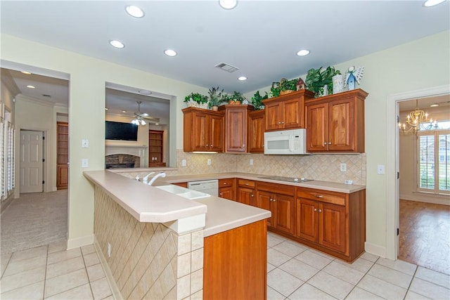 kitchen with white appliances, kitchen peninsula, light tile patterned floors, decorative backsplash, and ceiling fan with notable chandelier