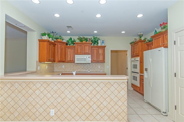 kitchen featuring white appliances, decorative backsplash, light tile patterned floors, and kitchen peninsula