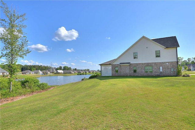view of property exterior with brick siding, a lawn, and a water view