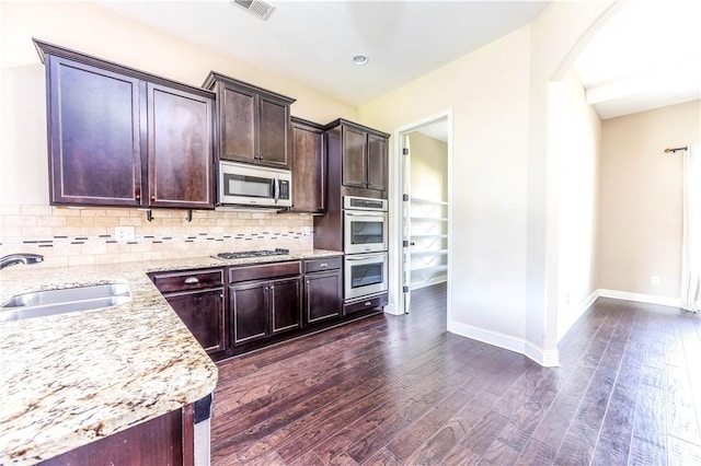 167 Vinci Way, Auburn, AL 36830 - kitchen with stainless steel appliances, dark wood finished floors, arched walkways, tasteful backsplash, and light stone counters