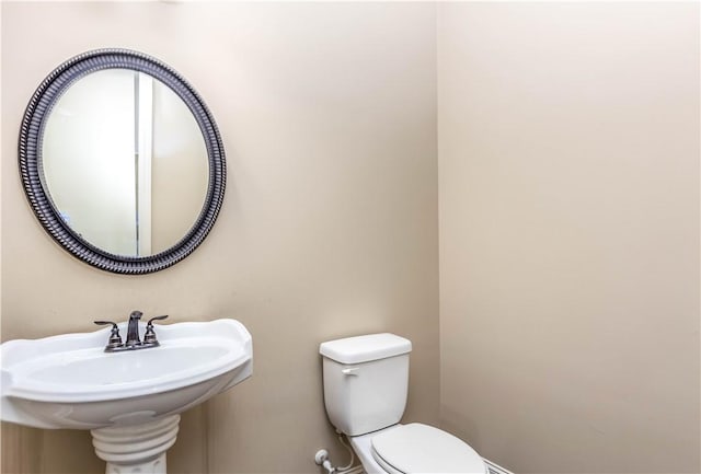 half bath featuring toilet and a sink