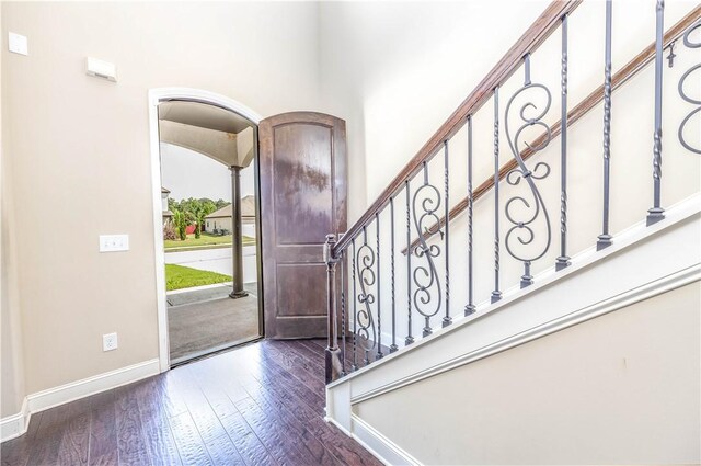 foyer entrance featuring baseboards, dark wood-type flooring, and stairway