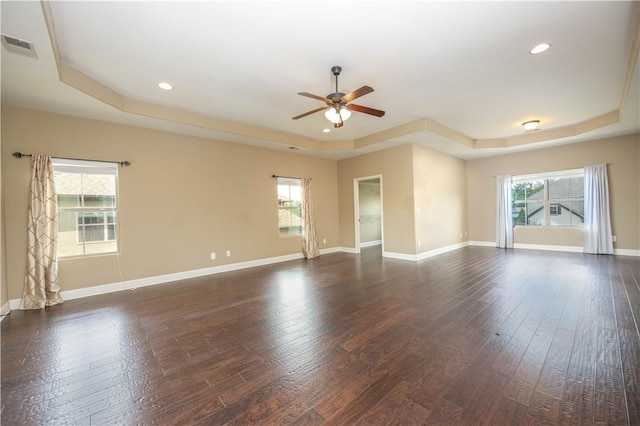 unfurnished room with a raised ceiling, ceiling fan, dark wood finished floors, recessed lighting, and baseboards