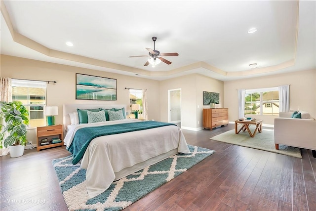 bedroom featuring a tray ceiling, wood-type flooring, baseboards, a ceiling fan, and recessed lighting