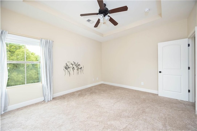 unfurnished room featuring a raised ceiling, carpet, and baseboards