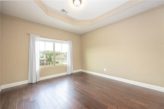 unfurnished room featuring dark wood-style flooring, baseboards, and a raised ceiling