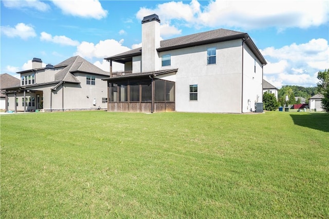 rear view of house featuring a chimney, a sunroom, a lawn, and central AC
