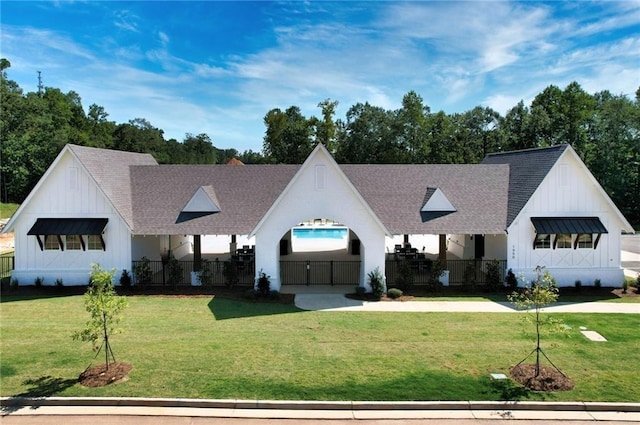 modern inspired farmhouse with board and batten siding, roof with shingles, a gate, and a fenced front yard