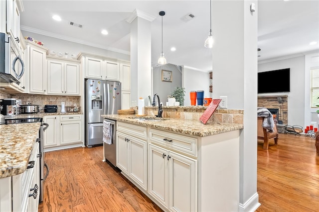 4164 Creekview Ct, Auburn, AL 36832 - kitchen featuring appliances with stainless steel finishes, light wood-type flooring, crown molding, light stone counters, and a fireplace