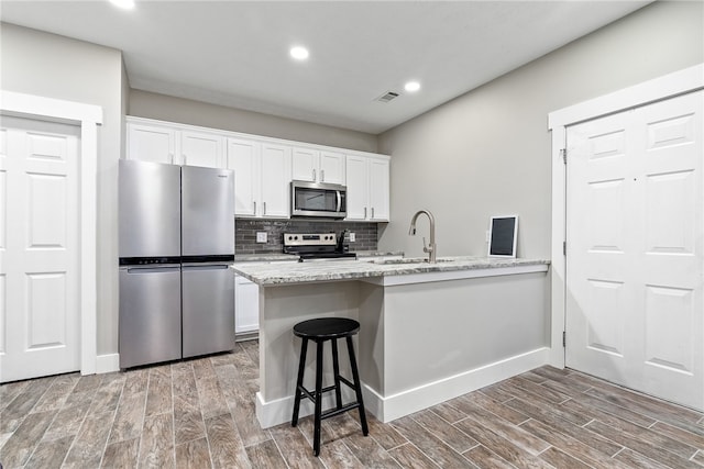 303 N Ross St Unit 104, Auburn, AL 36830 - kitchen with appliances with stainless steel finishes, a sink, white cabinets, recessed lighting, and decorative backsplash