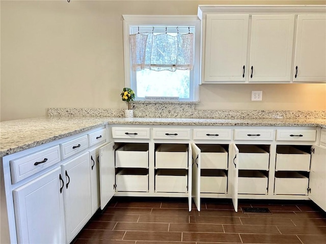 kitchen featuring light stone countertops and white cabinets