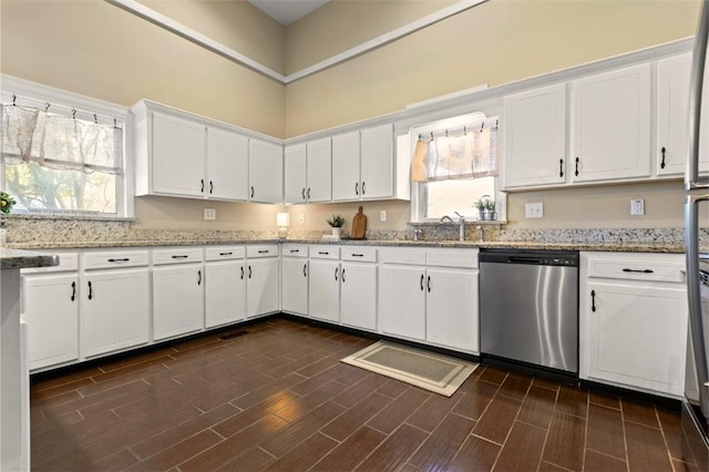 kitchen with white cabinetry, dishwasher, light stone countertops, and sink