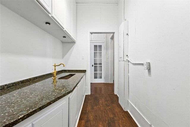 kitchen featuring white cabinetry, sink, dark stone countertops, and dark hardwood / wood-style floors