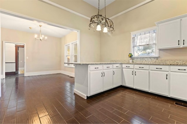 kitchen featuring a notable chandelier, white cabinets, light stone counters, and decorative light fixtures