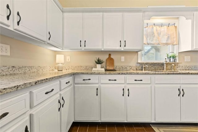 kitchen featuring white cabinetry, sink, and light stone counters