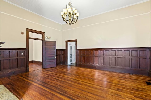 unfurnished room with an inviting chandelier, ornamental molding, and dark hardwood / wood-style flooring